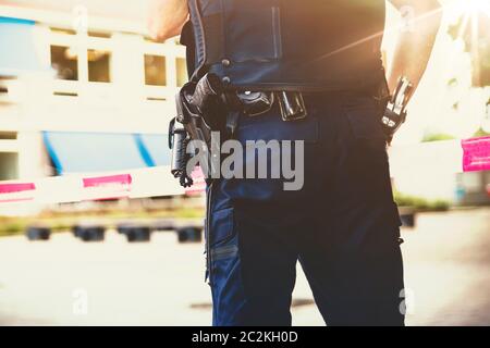 Polizist am Tatort. Rote Schutzfolie und Polizisten, pistole, handschellen und Gewehr Riemen Stockfoto