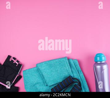 Sneakers von pink Frauen, eine Flasche Wasser, Handschuhe und ein Springseil für Sport auf einem rosa Hintergrund, Ansicht von oben, kopieren Raum Stockfoto