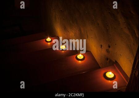 Dunkle Holztreppe, beleuchtet von Kerzen. Geht hinab ins Unbekannte, in Richtung Dunkelheit und Angst. Ein Schritt zum Unbekannten. Stockfoto