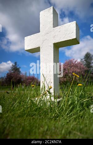 Weißes Kreuz auf dem Friedhof. Ein schlichtes weißes Kreuz markiert ein Grab. Stockfoto