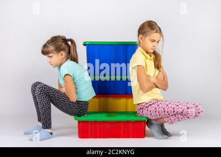 Zwei Mädchen gestritten, auf einem Kasten sitzen und von einander entfernt gedreht Stockfoto