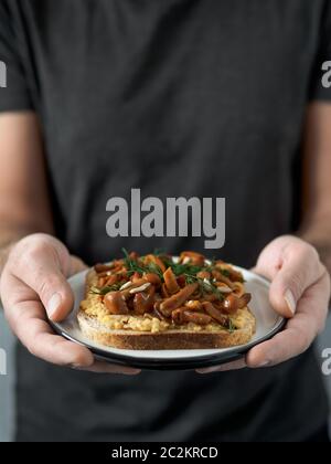 Veganes Sandwich mit Pilzen in männlichen Händen Stockfoto