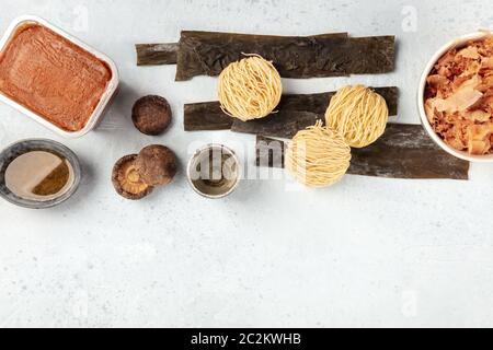 Ramen Zutaten. Getrockneter Seegrüsenkelch, Soba, Miso-Paste, Bonito-Flocken, Shiitake-Pilze, Sake, Mirin, Overhead-Shot, ein Stockfoto