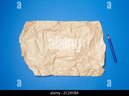 Blatt mit braun zerknittertem Papier für die Verpackung auf dunkelblauem Grund und Holzbleistift, Nahaufnahme Stockfoto
