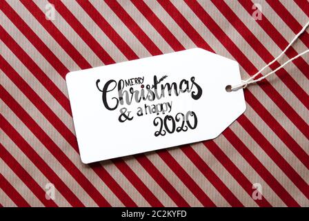 Etikett mit englischen Kalligraphie frohe Weihnachten und einen guten Rutsch ins Jahr 2020. Rote Verpackung Papier als Hintergrund Stockfoto
