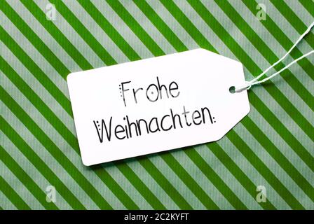 Etikett mit Deutschen Kalligraphie Frohe Weihnachten bedeutet, frohe Weihnachten. Grüne Verpackung Papier als Hintergrund Stockfoto