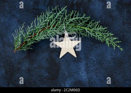 Ein weihnachtlicher Hintergrund mit einem weißen Stern, einem Ornament und einem Tannenzweig, über dem Kopf auf einem dunkelblauen Hintergrund mit Kopys Stockfoto