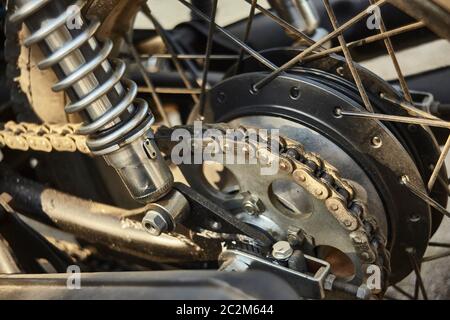 Detail des Kettengetriebes auf der Krone eines alten Oldtimer-Motorrades mit den Schalldämpfern auf der Seite, der Trommelbremse und der Speichen-Radstützen Stockfoto