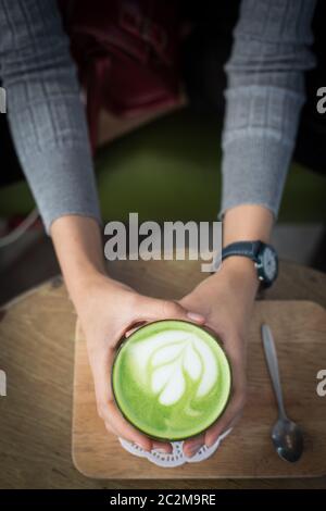 Tasse Matcha Grüner Tee in der Hand der Frau Stockfoto