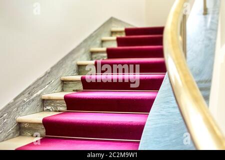 Elegante Treppe mit einem lila Samt Teppich auf der Treppe und einen Handlauf aus Messing. Eleganz und Luxus. Events und Auszeichnungen Stockfoto