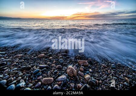 Eine Low Angle Seascape von Beach Rocks, während das Meerwasser zum Meer rauscht Stockfoto