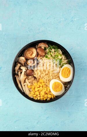 Ramen. Soba Nudeln mit gekochten Eiern, Shiitake-Pilze und Gemüse, von oben auf einem blauen Hintergrund mit einem Platz für geschossen Stockfoto