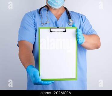 Arzt in der blauen Uniform und Latex Handschuhe hält eine grüne Halterung für Blatt Papier, leeren Raum für das Schreiben von Text auf weißem Hintergrund Stockfoto