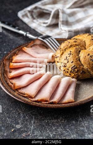 Geräucherter Schinken in Scheiben. Leckeres Schweinefleisch und Bun auf dem Teller. Stockfoto