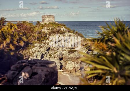 Felsige Landzunge mit Blick auf das Karibische Meer und einem alten Maya-Gebäude auf der Spitze: Wachturm des Maya-Komplexes von Tulum in Mexiko. Stockfoto