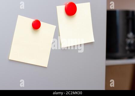 Blätter Papier mit Magneten auf Kühlschrank Küche. Platz für Text. Modell Stockfoto