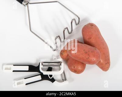 Kartoffeln und Kartoffelpresse isoliert auf weißem Hintergrund Stockfoto