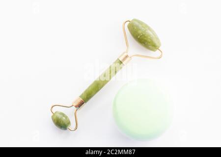 Massagerolle für das Gesicht mit zwei Köpfen aus Jadestein. Und ein Glas Gesichtscreme. Stockfoto