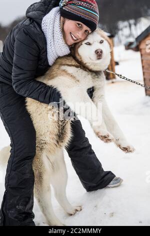 Junge Frau im Winter spielt mit einem sibirischen Hund Stockfoto