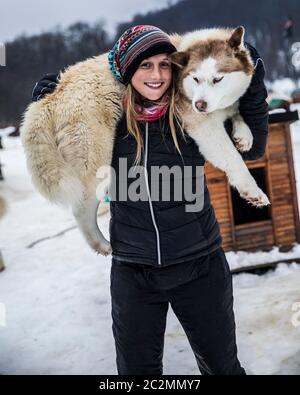 Junge Frau im Winter spielt mit einem sibirischen Hund Stockfoto