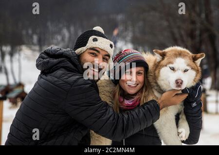 Paar mit einem sibirischen Hund im Winter von Schnee umgeben. Stockfoto