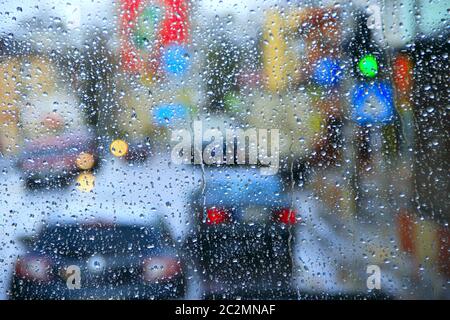 Regen draußen Fenster auf Hintergrund der Lichter der Stadt. Wassertropfen fallen bei Regen auf das Glas Stockfoto