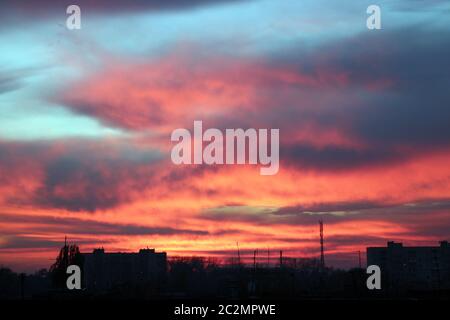 Purpurner Sonnenuntergang über dem mehrstöckigen Haus. Abendliche Stadtlandschaft. Stadtlandschaft. Abenddämmerung in der Stadt Stockfoto