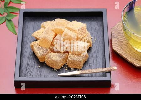 Japanische Süßwaren, Warabi mochi traditionelle Süßigkeiten auf rotem Hintergrund Stockfoto