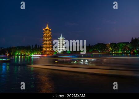 Touristenboote, die vor den beleuchteten Pagoden-Türmen der Sonne und des Mondes am Shanhu oder Shan See in Guilin, Guangxi Provinz, China segeln Stockfoto