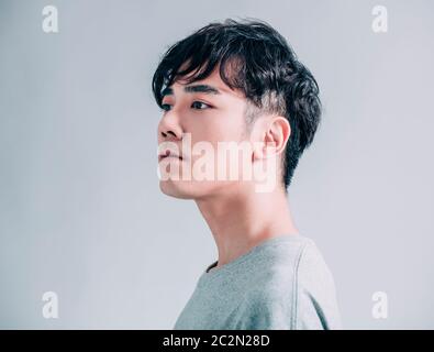 Seitenansicht des jungen asiatischen gutaussehenden Mannes isoliert auf grauem Hintergrund Stockfoto