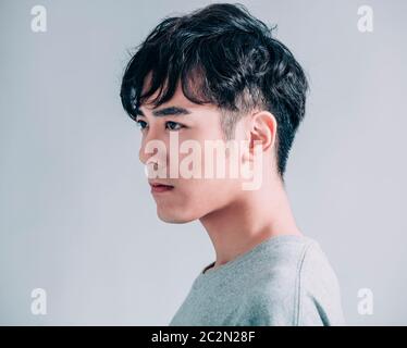 Seitenansicht des jungen lächelnden gutaussehenden Mannes isoliert auf grauem Hintergrund Stockfoto