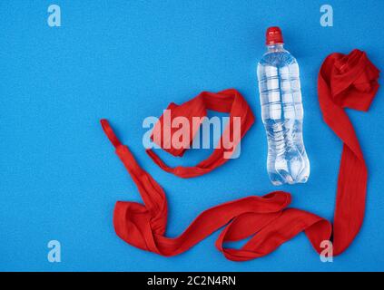 Paar rote Textilbandagen für das Wickeln von Händen an Sportler vor dem Sporttraining und eine Flasche Wasser auf blauem Grund, Draufsicht Stockfoto