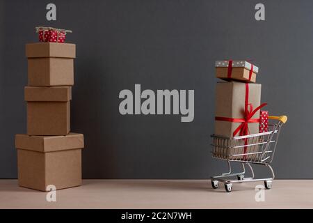 Geschenkboxen mit roter Schleife-Knoten und Warenkorb auf dunklem Hintergrund Stockfoto