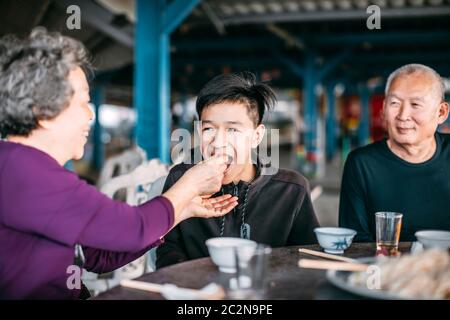 Großmutter füttert ihren Teenager-Enkel im Restaurant Stockfoto