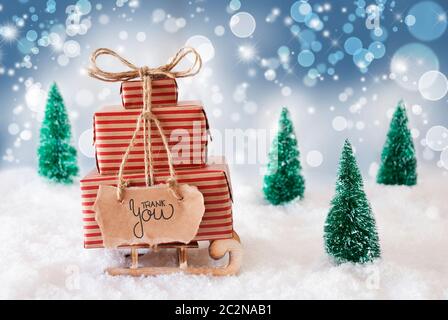 Schlitten mit Weihnachtsgeschenk und Label mit englischen Kalligraphie Danke. Schnee mit Weihnachtsbaum und Blau schimmernden Hintergrund Stockfoto
