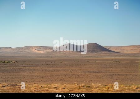 Düstere Wüstenlandschaft mit rötlichen Sandstränden und Berg- und Felsformationen im Norden Saudi Arabiens Stockfoto