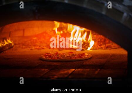 Professionelle Pizzaofen. Ein gutes Feuer brennt im Ofen. Pizza in den Ofen. Kochen Pizza im Cafe. Stockfoto