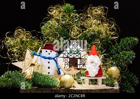 Schneemann fegt Schnee vor einem Haus und zieht einen Schlitten mit Santa Claus Stockfoto