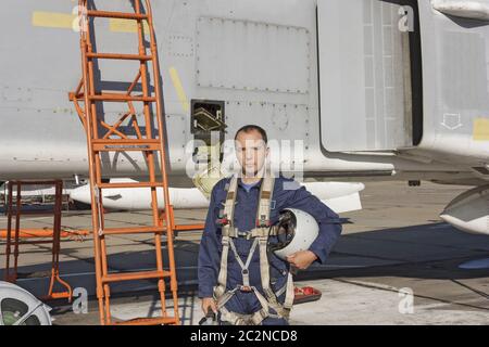 Militärpilot mit Helm in seiner Hand Stand in der Nähe ein Düsenflugzeug Stockfoto