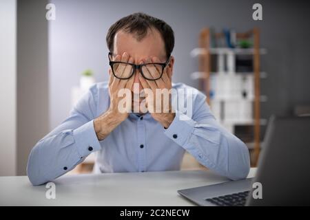 Der Mann mit der Hand über das Gesicht mit Brille im Büro Stockfoto
