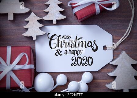 Ein Etikett mit englischen Kalligraphie Frohe Weihnachten und guten Rutsch ins Jahr 2020. Weihnachtsdekoration wie Geschenke und Bäumen. Holz- Hintergrund Stockfoto
