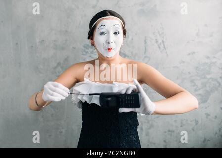 MIME-Künstlerin mit Handy durchführen. Frau Zirkusclown. Pantomime-Theater-Komiker mit weißem Make-up Maske auf Gesicht Stockfoto