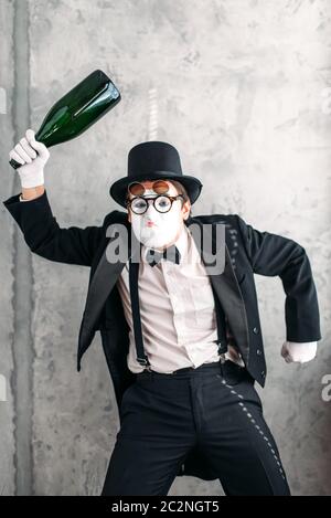 Pantomime mit großen Flasche Alkohol einen betrunkenen Mann durchführen. Comedy-Pantomime-Künstler im Anzug, Handschuhe, Brille, Make-up Maske und Hut Stockfoto