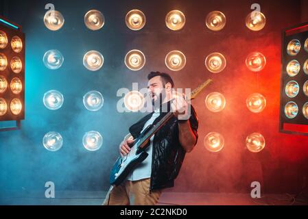 Männliche Solo-Musiker mit Elektro-Gitarre auf der Bühne mit den Dekorationen der Lichter. Musikalische Unterhaltung. Stockfoto