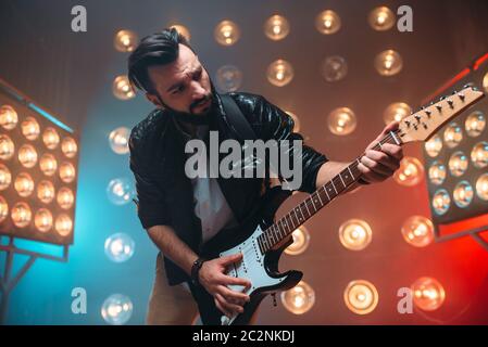 Männliche Solo-Musiker mit Elektro-Gitarre auf der Bühne mit den Dekorationen der Lichter. Musikalische Unterhaltung. Stockfoto