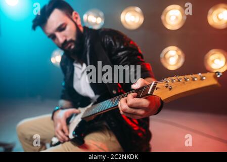 Männliche Solo-Musiker mit Elektro-Gitarre auf der Bühne mit den Dekorationen der Lichter. Musikalische Unterhaltung. Stockfoto