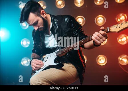 Männliche Solo-Musiker mit Elektro-Gitarre auf der Bühne mit den Dekorationen der Lichter. Musikalische Unterhaltung. Stockfoto