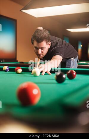 Fokussierter Mann schlägt einen Billardball. Blick aus einer Tasche Billard-Tisch. Stockfoto