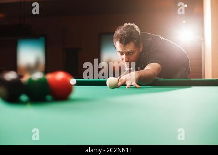 Spieler bricht eine Pyramide in Billard. Nachtleben. Billardzimmer im Hintergrund. Stockfoto