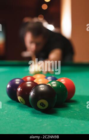 Spieler bricht eine Pyramide in Billard. Nachtleben. Billardzimmer im Hintergrund. Stockfoto